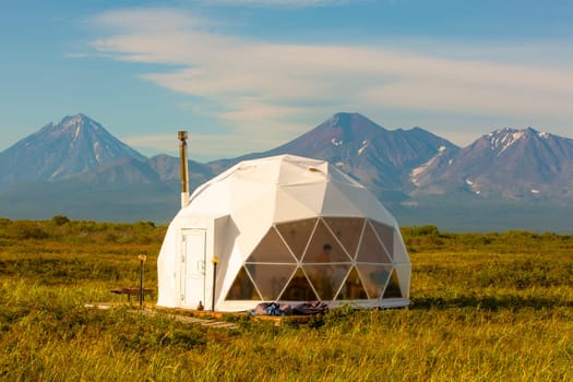 The Glamping house and volcano, rural landscape, tent houses in Kamchatka peninsula. Selective focus.