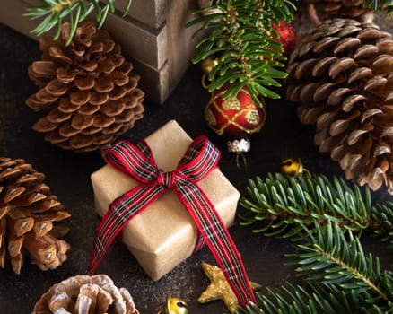Wrapped gift boxes between Christmas decorations, pine cones and green fir branches close up. Christmas or New Year Holiday atmosphere flat lay