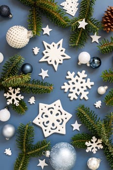 White Christmas decorations and fir tree branches on a blue top view.. New Year and Christmas holiday atmospheric flat lay with baubles, snowflakes and stars
