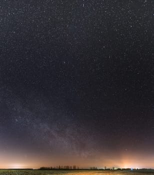Night Starry Sky With Glowing Stars Above Countryside Landscape. Milky Way Galaxy And Rural Field Meadow In Early Spring.