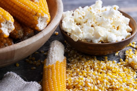 Harvesting popcorn from the cob with a bowl of popped corn surrounded by kernels and cob with kernels partially removed.