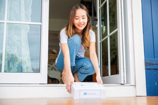 Close up hands of sick Asian woman sitting at door to receive medication first aid pharmacy box package from hospital delivery service at floor home, drugstore internet online medical business