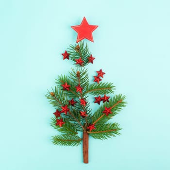 Christmas tree made from fir branches, red stars and a cinnamon stick as the trunk, greeting card with copy space