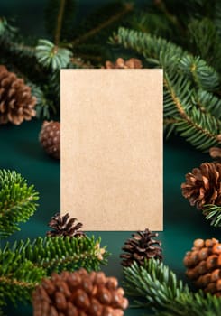 vertical blank card between fir branches and pine cones on green close up, mockup. Christmas or New Year greeting card template, Holiday winter composition