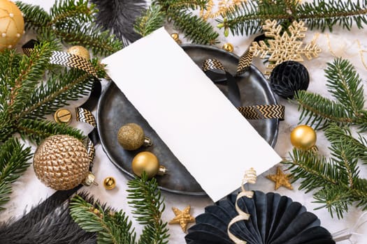 Black and golden Table setting with ornaments and fir tree branches, card mockup. Christmas or New Year menu on marble table close up, copy space. Winter season, restaurant holiday catering