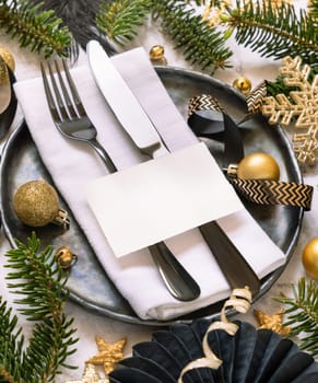 Black and golden Table setting with ornaments and fir tree branches close up, place card mockup. Christmas or New Year atmospheric composition flat lay, copy space.