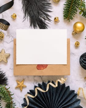 Horizontal Paper card between black and golden Christmas decorations and fir tree branches top view. Winter composition with blank invitation card Mockup, copy space