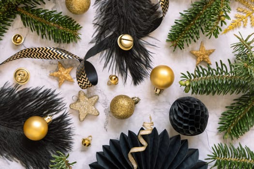 Black and golden Christmas ornaments and baubles and fir branches on marble top view. Dark winter flat lay for Christmas, New Year, Birthday, Anniversary