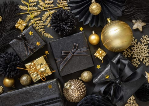 Christmas Gift Box with a bow near black and golden ornaments and baubles top view. Dark winter flat lay for Christmas, New Year, Birthday, Anniversary