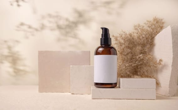 Brown one pump bottle with blank label on stones near pampas grass on light beige close up, packaging mockup. Skincare beauty product, lotion or cleanser. Natural eco friendly cosmetics