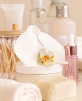 Natural cosmetic jars and skin care accesories with white orchid flower on light beige close up. Beauty products for everyday woman face care routine, Spa Treatments