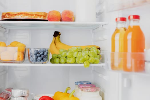 Front View of open two door fridge or refrigerator door filled with fresh fruits, vegetables, juice, full of healthy food items and ingredients inside. Electric Kitchen and Domestic Major Appliances