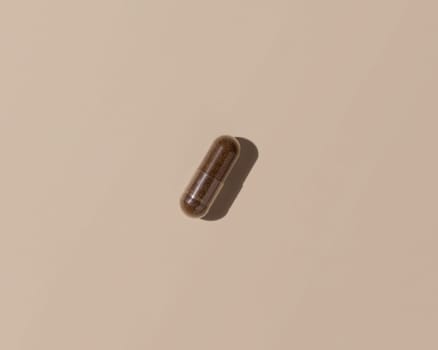 Brown medical capsule on light beige top view, hard shadows. Preventive medicine and healthcare, taking dietary supplements and vitamins. Minimal composition