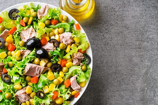 Healthy Green salad with tuna and vegetable on grey background close up. Mexican corn salad.