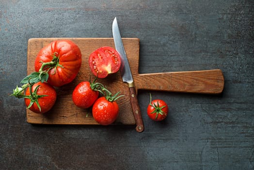 Fresh tomatoes in cutting board on a dark background. Harvesting tomatoes. Cooking healthy meal.