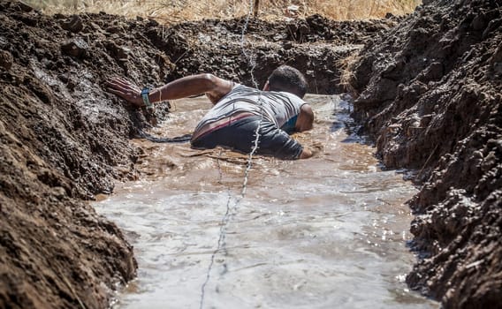 Merida, Spain - Sept 11th, 2022: FarinatoRace Merida 2022. Toughest obstacle course in the world. Trench flooded with barbed wire