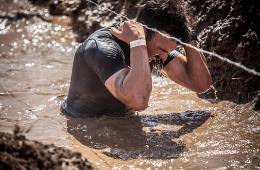 Merida, Spain - Sept 11th, 2022: FarinatoRace Merida 2022. Toughest obstacle course in the world. Trench flooded with barbed wire