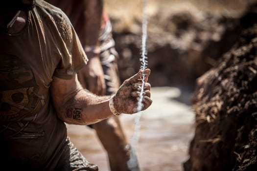 Merida, Spain - Sept 11th, 2022: FarinatoRace Merida 2022. Toughest obstacle course in the world. Trench flooded with barbed wire