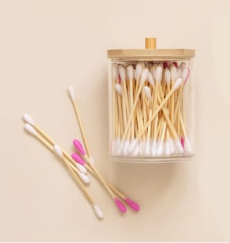 Bamboo cotton buds in a jar on light beige, top view. Organic skincare product for everyday beauty routine. Eco friendly Biodegradable cotton swabs..