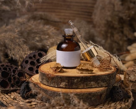 Opened glass bottle on wood near natural boho decorations close up, cosmetics label mockup. Eco friendly Skincare beauty product, serum or essence. Bohemian composition with dried leaves and flowers.
