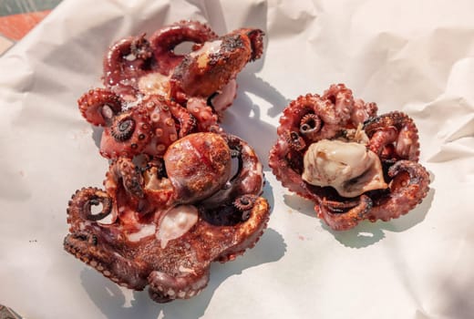 Freshly grilled octopused on a plate outdoor, Italy. Traditional Mediterranean cuisine. Eating seafood outdoor during summer time. Rustic style grilled octopuses bbq