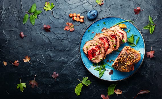 Appetizing roll roast with autumn plum and nuts.Pork porchetta.Copy space