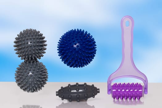 Closeup of various therapy and fitness equipment, such as massage balls or hedgehog balls and roller for health therapie on table over abstract background.