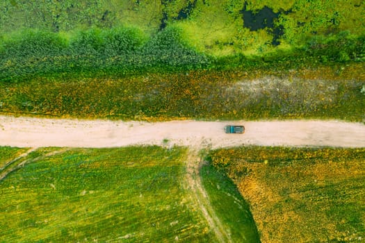 Aerial View Of Car SUV Parked On Countryside Road Between Rural Field And Marsh Bog Swamp Landscape. Summer Day.