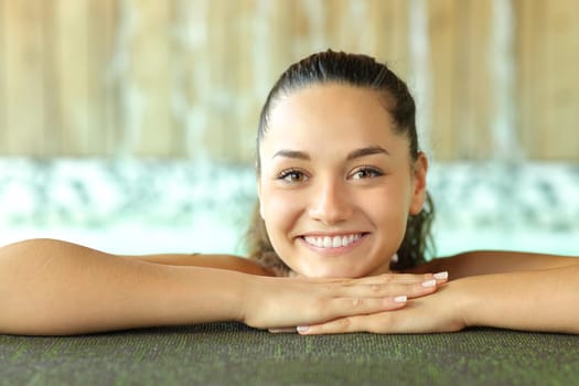 Front view portrait of a beautiful woman in spa looking at camera smiling