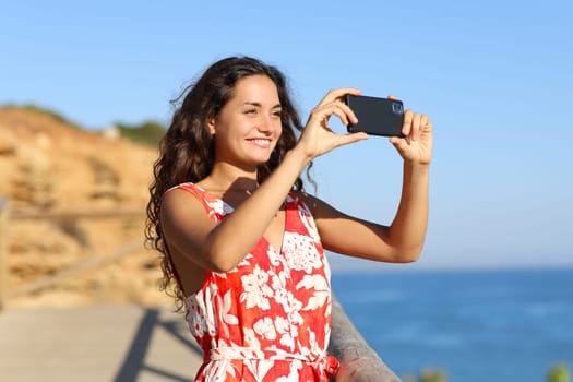 Tourist on the beach taking photo with smart phone a sunny summer day on vacation