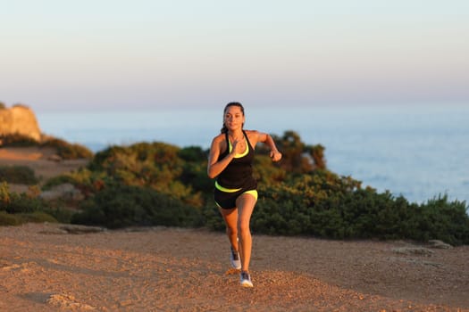 Front view portrait of a runner running at sunset on the beach