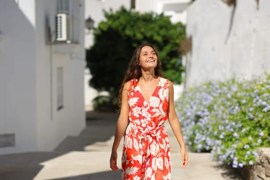 Front view portrait of a happy tourist walking sightseeing in a white town street on summer vacation