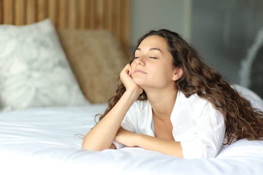 Woman with eyes closed relaxing lying on the bed