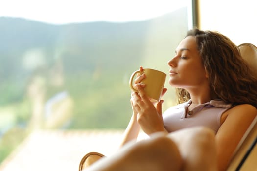 Woman sitting on a chair relaxing drinking coffee at home