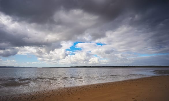 Threatening rain clouds forming over the Great Sandy Straits, Fraser Coast, Poona, Queensland. Mud flats are showing as the tide runs out.