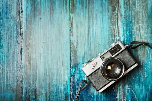Vintage photo camera on grunge blue wooden background with copyspace.