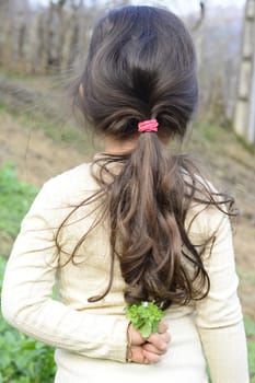 5 years old girl holding wildflowers at her back