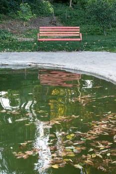 Empty bench reflection on water puddle