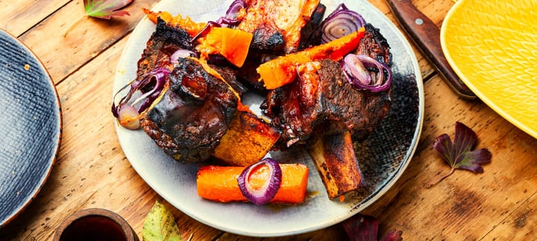 Beef ribs BBQ on wooden table.Baked beef meat with slices of pumpkin
