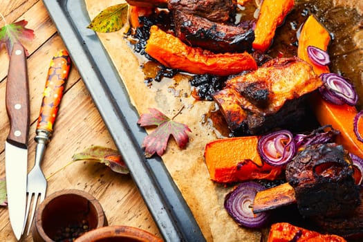 Beef ribs BBQ on wooden table.Baked beef meat with slices of pumpkin