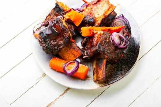 Beef ribs BBQ on wooden table.Baked beef meat with slices of pumpkin
