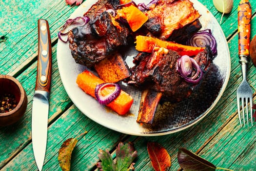 Beef ribs BBQ on wooden table.Baked beef meat with slices of pumpkin