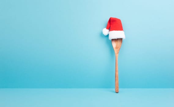Blank paper with a wooden spoon and a red Santa Claus hat, christmas greeting card, copy space for a recipe for the holiday
