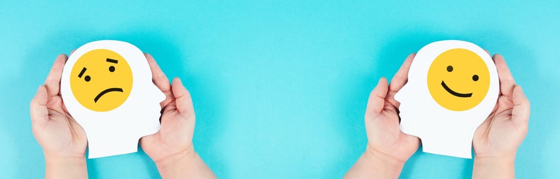 Holding a head with a sad and a happy face in the hands, mental health concept, positive and negative mindset, depression, support and evaluation symbol, emotion