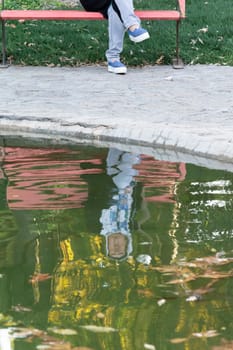 Young woman reflection on water puddle at park