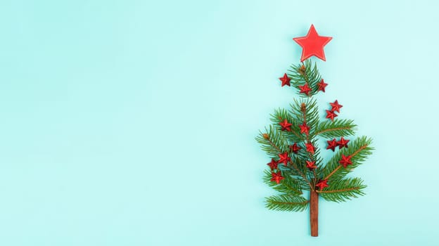 Christmas tree made from fir branches, red stars and a cinnamon stick as the trunk, greeting card with copy space