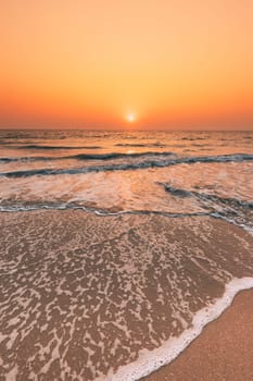 Sunset Sun Above Sea. Natural Sunrise Sky Warm Colors Over Ripple Sea. Ocean Water Foam Washing Sandy Beach At Sunset.