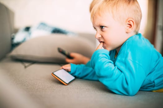 Little Caucasian Boy Playing Games On Phone Thoughtfully.