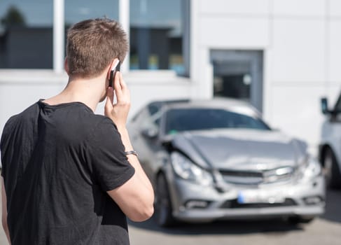 Young man on the phone after car crash