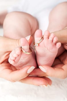 Baby feet with wedding rings - parenting concept